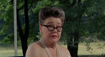 Movie still from “The Swimmer” (1968), directed by Sydney Pollack – An older woman wearing pearls and wearing glasses; Close Up shot, Over the shoulder angle