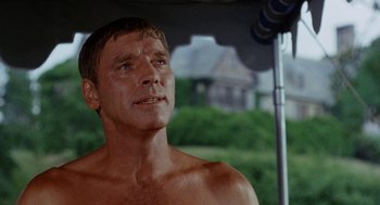 Movie still from “The Swimmer” (1968), directed by Sydney Pollack – A shirtless man standing under an awning; Close Up shot, Low angle