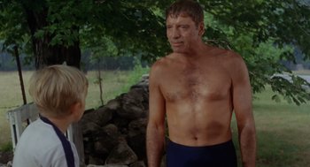 Movie still from “The Swimmer” (1968), directed by Sydney Pollack – A shirtless man standing next to a young boy; Medium shot, Over the shoulder angle