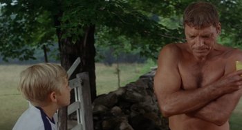 Movie still from “The Swimmer” (1968), directed by Sydney Pollack – A man and a boy standing next to each other in front of a tree; Medium shot, Low angle