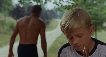 Movie still from “The Swimmer” (1968), directed by Sydney Pollack – A young boy sitting next to an adult on a path; Close Up shot, Over the shoulder angle