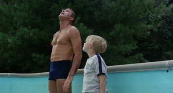 Movie still from “The Swimmer” (1968), directed by Sydney Pollack – A man and a boy standing next to each other in swimming trunks; Medium shot, Low angle
