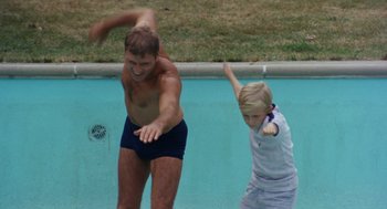 Movie still from “The Swimmer” (1968), directed by Sydney Pollack – A man and a boy playing frisbee in a swimming pool; Wide shot, Low angle