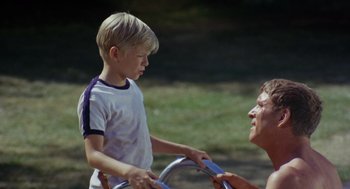 Movie still from “The Swimmer” (1968), directed by Sydney Pollack – An older woman and a young boy are playing with a toy; Medium shot, High angle