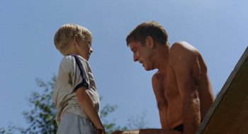 Movie still from “The Swimmer” (1968), directed by Sydney Pollack – A man and a boy standing next to each other; Medium shot, Low angle