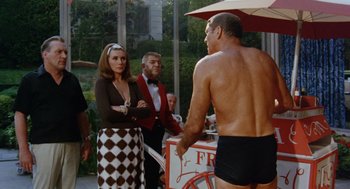 Movie still from “The Swimmer” (1968), directed by Sydney Pollack – A man in black and white bathing suit standing next to a woman in a black and white checkered skirt; Medium shot, Over the shoulder angle