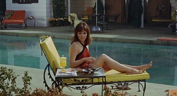 Movie still from “The Swimmer” (1968), directed by Sydney Pollack – A woman sitting on top of a lounge chair next to a swimming pool; Medium shot, High angle