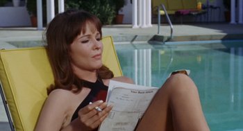 Movie still from “The Swimmer” (1968), directed by Sydney Pollack – A woman sitting in a chair by a pool; Medium shot, High angle