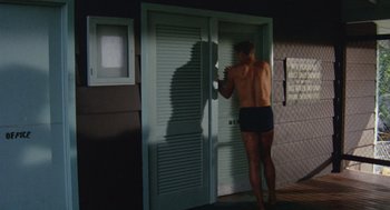 Movie still from “The Swimmer” (1968), directed by Sydney Pollack – A shirtless man standing in front of an open door; Medium shot, Low angle