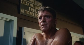 Movie still from “The Swimmer” (1968), directed by Sydney Pollack – A shirtless man with a sign in front of him; Close Up shot, Low angle