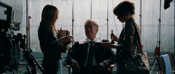 Movie still from “The Switch” (2010), directed by Josh Gordon – A man sitting in a chair being shaved by two women; Medium shot, Over the shoulder angle