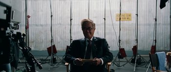 Movie still from “The Switch” (2010), directed by Josh Gordon – A man in a suit and tie sitting in a chair; Medium shot, Over the shoulder angle