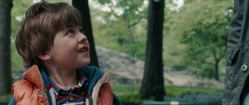 Movie still from “The Switch” (2010), directed by Josh Gordon – A young boy is smiling in front of some trees; Close Up shot, Over the shoulder angle