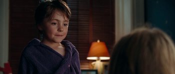 Movie still from “The Switch” (2010), directed by Josh Gordon – A little boy wearing a purple robe in front of a lamp; Close Up shot, Over the shoulder angle