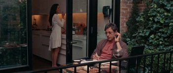 Movie still from “The Switch” (2010), directed by Josh Gordon – A man sitting at a table talking on the phone while a woman watches; Medium shot, Over the shoulder angle