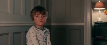 Movie still from “The Switch” (2010), directed by Josh Gordon – A young boy wearing pajamas sitting in front of a wall; Close Up shot, Over the shoulder angle