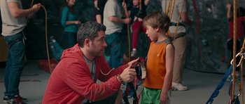 Movie still from “The Switch” (2010), directed by Josh Gordon – A man showing a child how to use a harness; Medium shot, Over the shoulder angle