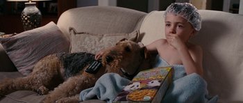 Movie still from “The Switch” (2010), directed by Josh Gordon – A boy sitting on a couch next to a brown dog; Medium shot, High angle