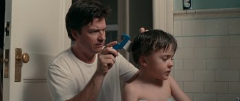 A young boy getting his hair cut by an adult