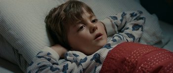 Movie still from “The Switch” (2010), directed by Josh Gordon – A young boy laying in bed with his head resting on a pillow; Close Up shot, High angle