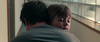 Movie still from “The Switch” (2010), directed by Josh Gordon – A young boy hugging his father in the arms of him; Close Up shot, Over the shoulder angle