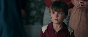 Movie still from “The Switch” (2010), directed by Josh Gordon – A young boy with blood on his face looking at the camera; Close Up shot, Over the shoulder angle