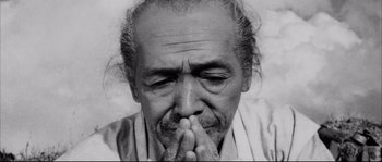 Movie still from “The Sword of Doom” (1966), directed by Kihachi Okamoto – An old man is sitting down with his hands folded over his face; Close Up shot, Low angle