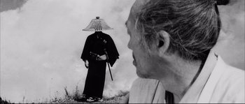 Movie still from “The Sword of Doom” (1966), directed by Kihachi Okamoto – An old man looking at an older man wearing a hat; Close Up shot, Over the shoulder angle