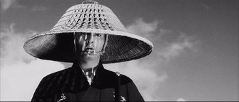 Movie still from “The Sword of Doom” (1966), directed by Kihachi Okamoto – A man wearing a hat and smoking a cigarette; Close Up shot, Low angle