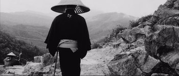 Movie still from “The Sword of Doom” (1966), directed by Kihachi Okamoto – A person with a hat on a mountain side; Medium shot, Low angle