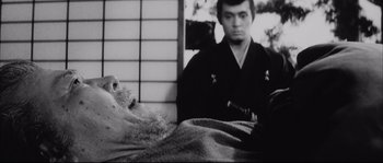 Movie still from “The Sword of Doom” (1966), directed by Kihachi Okamoto – An old photo of a man with a sword in front of him; Close Up shot, Low angle