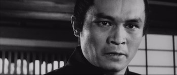Movie still from “The Sword of Doom” (1966), directed by Kihachi Okamoto – Black and white photograph of a man looking at the camera; Close Up shot, Low angle
