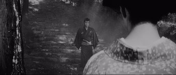 Movie still from “The Sword of Doom” (1966), directed by Kihachi Okamoto – A man in a kimono standing in front of a stone wall; Medium shot, Over the shoulder angle
