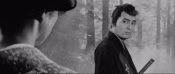 Movie still from “The Sword of Doom” (1966), directed by Kihachi Okamoto – A black and white photo of a man and a dog; Close Up shot, Low angle