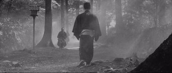 Movie still from “The Sword of Doom” (1966), directed by Kihachi Okamoto – Two people in a forest with smoke coming out of the trees; Wide shot, Low angle