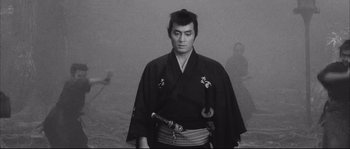 Movie still from “The Sword of Doom” (1966), directed by Kihachi Okamoto – A man in a black robe holding a sword; Medium shot, Low angle