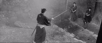 Movie still from “The Sword of Doom” (1966), directed by Kihachi Okamoto – A man holding a sword while standing on top of a hill; Wide shot, Over the shoulder angle