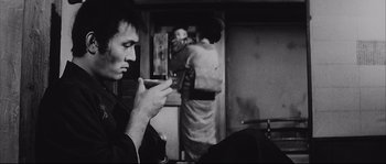 Movie still from “The Sword of Doom” (1966), directed by Kihachi Okamoto – A man looking at his cell phone in front of a mirror; Medium shot, Over the shoulder angle