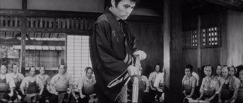 Movie still from “The Sword of Doom” (1966), directed by Kihachi Okamoto – A man holding a sword in front of a group of people; Medium shot, Low angle
