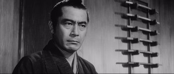 Movie still from “The Sword of Doom” (1966), directed by Kihachi Okamoto – An old black and white photo of a man in a kimono; Close Up shot, Low angle