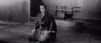 Movie still from “The Sword of Doom” (1966), directed by Kihachi Okamoto – A man sitting on the ground holding a sword; Medium shot, High angle