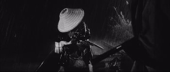 Movie still from “The Sword of Doom” (1966), directed by Kihachi Okamoto – A person with a hat holding a sword in the dark; Medium shot, Low angle