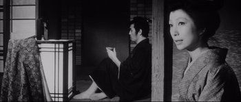 Movie still from “The Sword of Doom” (1966), directed by Kihachi Okamoto – A man sitting on the floor in front of a television; Medium shot, Low angle