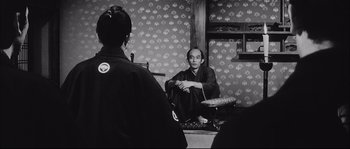 Movie still from “The Sword of Doom” (1966), directed by Kihachi Okamoto – A man sitting on the ground in front of another man; Medium shot, Over the shoulder angle
