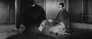 Movie still from “The Sword of Doom” (1966), directed by Kihachi Okamoto – A man sitting on the ground with a sword in his hand; Medium shot, Over the shoulder angle