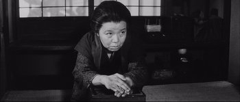 Movie still from “The Sword of Doom” (1966), directed by Kihachi Okamoto – An older japanese woman is leaning on a laptop computer; Medium shot, Low angle