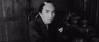 Movie still from “The Sword of Doom” (1966), directed by Kihachi Okamoto – A man in a black and white photo smoking a cigarette; Close Up shot, Low angle