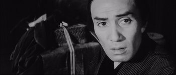 Movie still from “The Sword of Doom” (1966), directed by Kihachi Okamoto – A black - and - white photo of a man looking at the camera; Close Up shot, Low angle