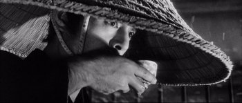 Movie still from “The Sword of Doom” (1966), directed by Kihachi Okamoto – A person holding a cup under a straw hat; Close Up shot, Low angle