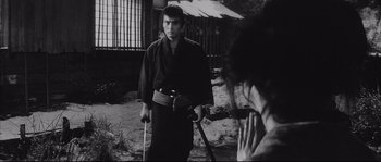 Movie still from “The Sword of Doom” (1966), directed by Kihachi Okamoto – A man holding a sword in his hand and looking at a woman; Medium shot, Over the shoulder angle